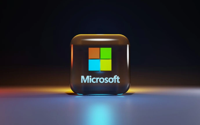 A glossy glass cube with the Microsoft logo on a dark surface